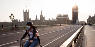 A cyclist wearing a face mask rides across a near-deserted Westminster Bridge in London, England, on April 8, 2020. (Photo by David Cliff/NurPhoto via Getty Images)