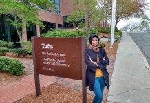 Dhini posing next to a sign at the Fletcher School