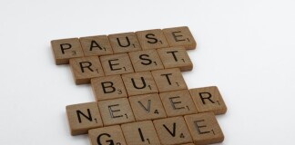 A wooden block puzzle with the motivating words "pause, rest, but never give up"